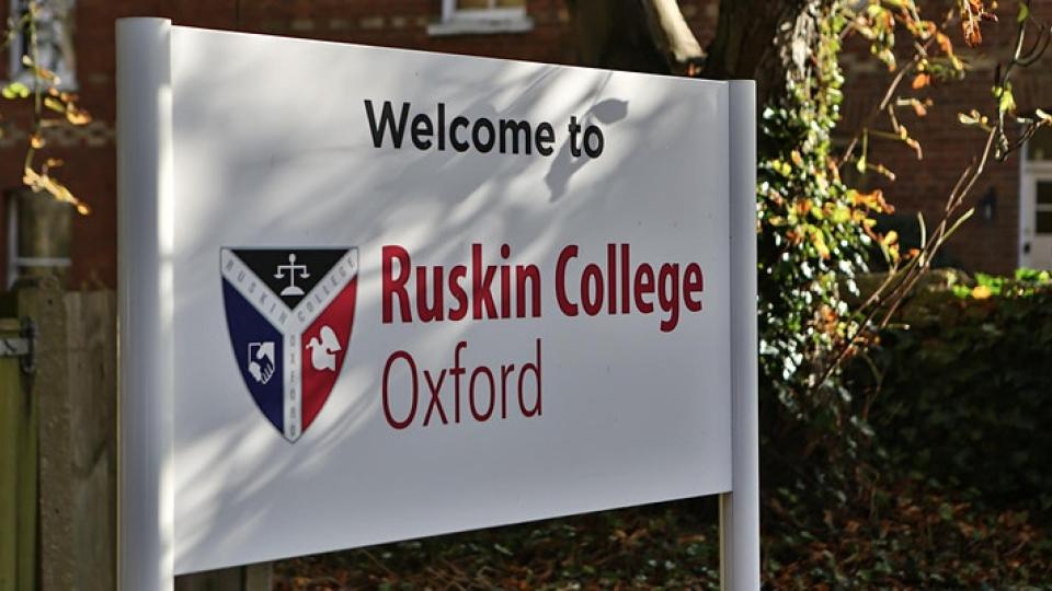 A Ruskin College white sign stating "Welcome to Ruskin College Oxfrod" with the Ruskin College logo