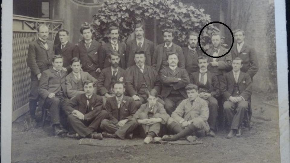 Bertram Wilson is circled in a group photo of twenty men dressed in suits and ties.