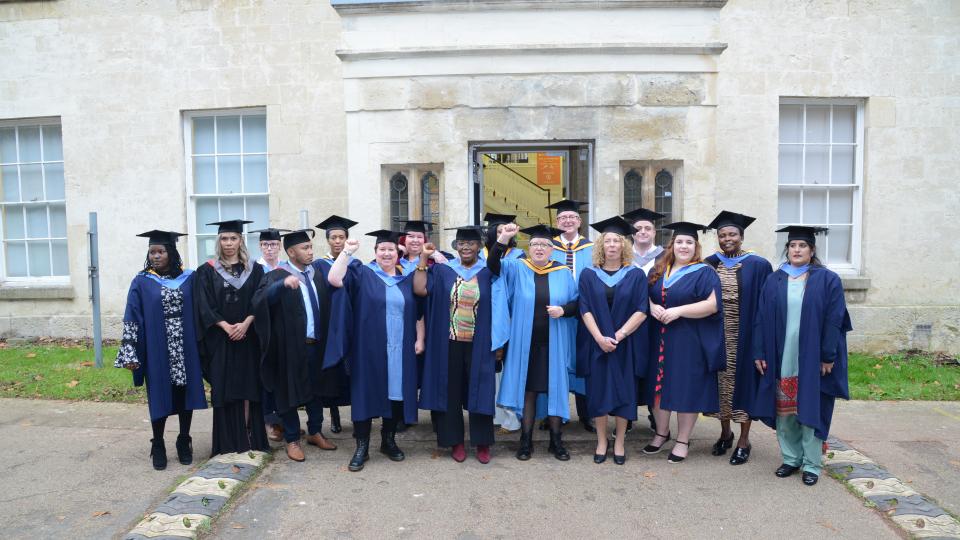 A group of Ruskin College graduates with gowns and mortar board hats on.