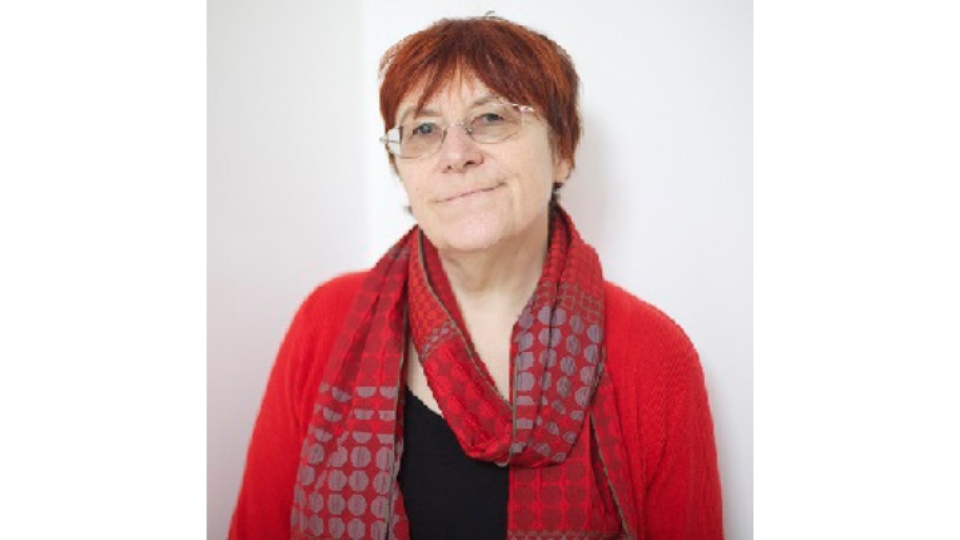 Hilda Kean has glasses on and is wearing a red cardigan and scarf.