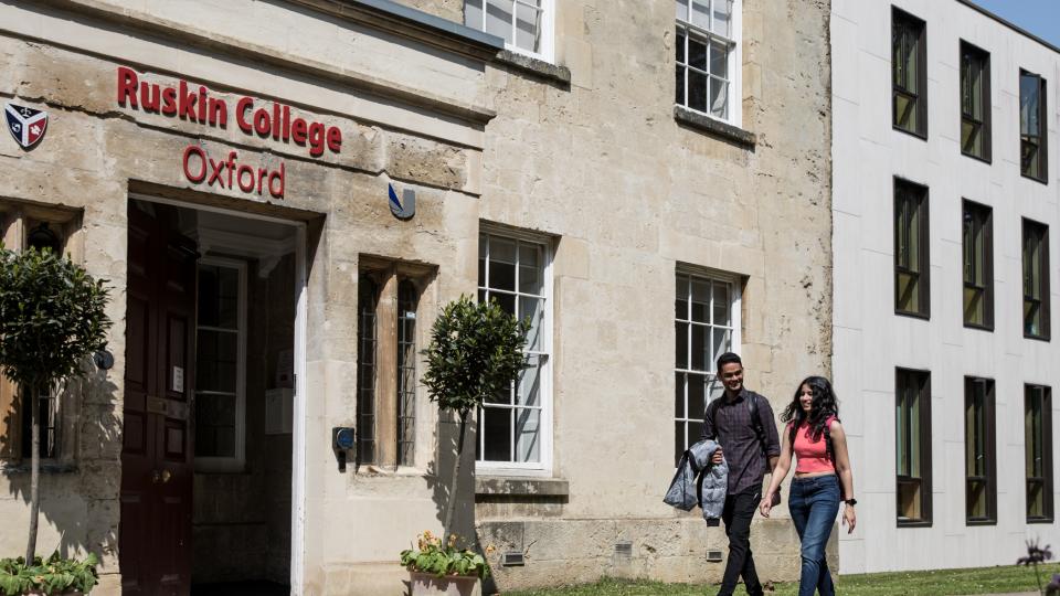 Two students walking outside the entrance to Ruskin College Oxford.
